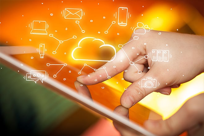 A finger pointing at a screen with cloud technologies floating above it.